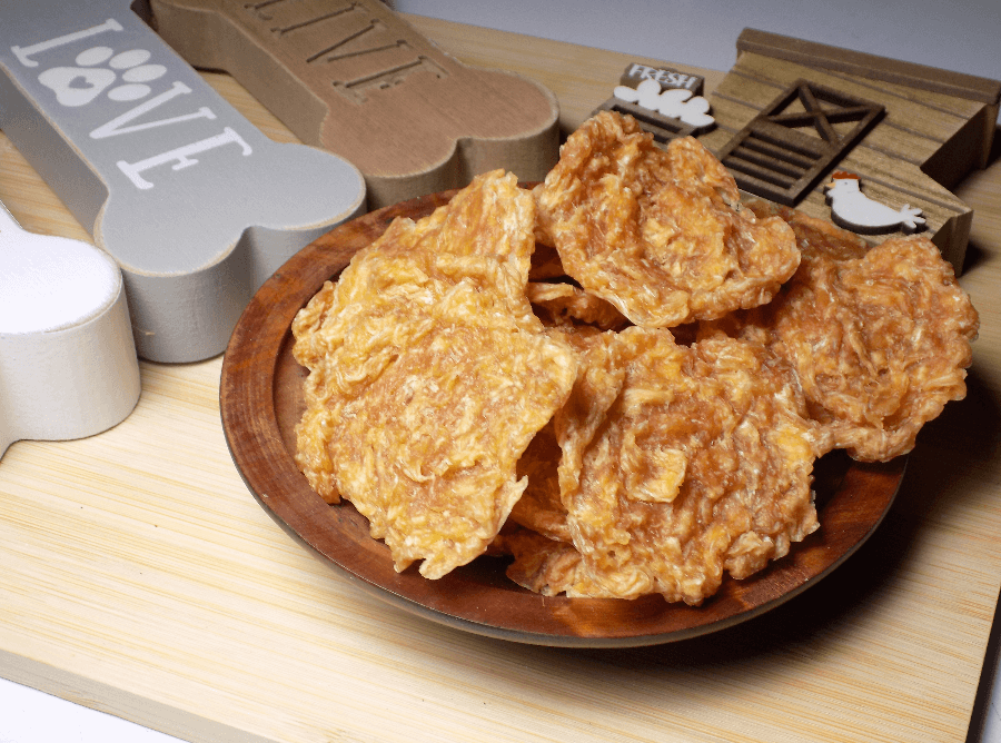Dog treats on a wooden plate with a 'LOVE' sign and dog-themed decor in the background.