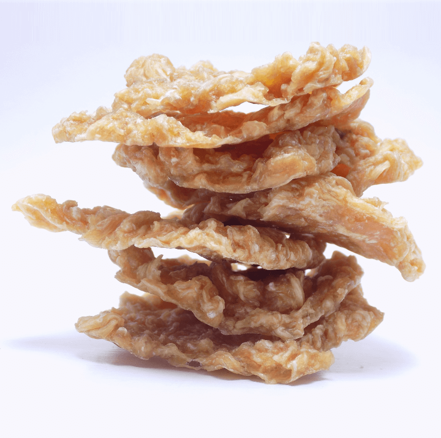 Stack of crispy dehydrated chicken pet treats on a white background