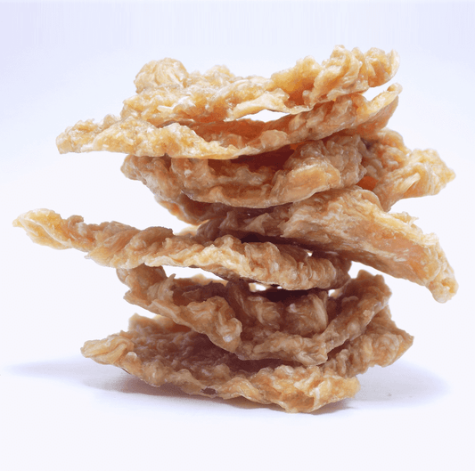 Stack of crispy dehydrated chicken pet treats on a white background